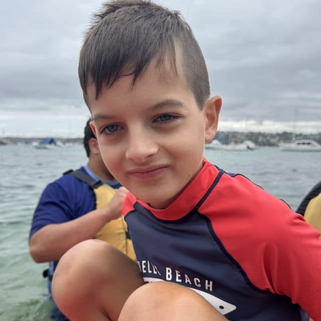 A young participant out on the water, smiling at the camera